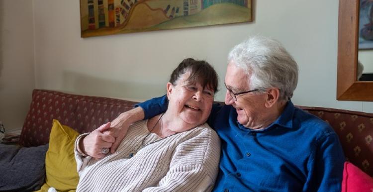 grey_haired_man_cuddling_brown_haired_woman_on_the_sofa