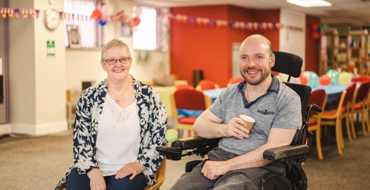 Older_lady_caring_for_a_disabled_man_in_a_wheelchair