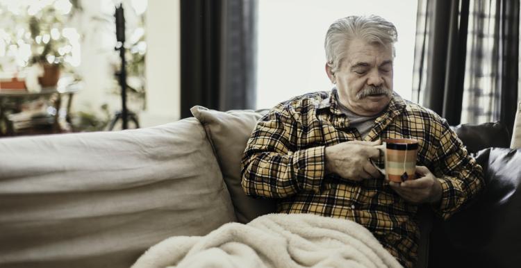 Old_man_cold_sitting_at_home_with_a_blanket_and_a_warm_drink