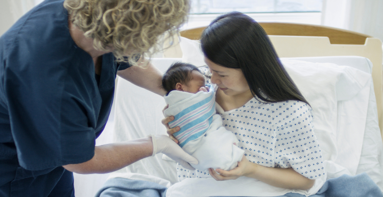 white-midwife-looking-after-an-asian-mother-and-child