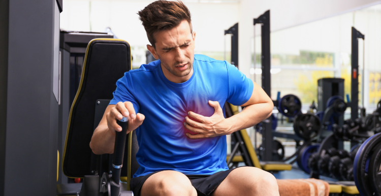 young_man_sitting_in_the_gym_clutching_his_chest