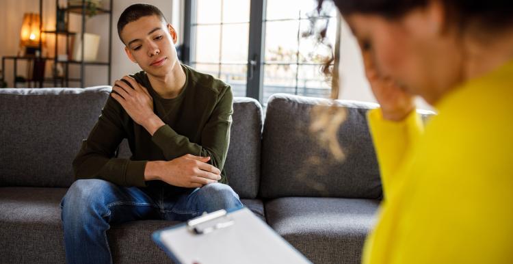 young_man_sitting_on_a_sofa_listening_to_a_woman_therapist