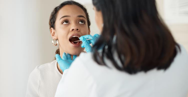 Young_woman_with_her_mouth_open_being_examined_by_a_dentist