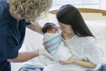 white-midwife-looking-after-an-asian-mother-and-child