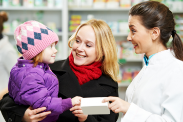 Woman_holding_a_child_wearing_a_hat_visting_a_pharmacist_all_are_smiling
