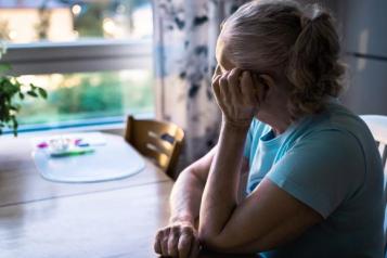 woman_sitting_at_a_table_holding_her_face_looking_out_of_the_window