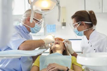 Male_dentist_and_female_dental_assistant_doing_a_dental_check_on_a_young_woman